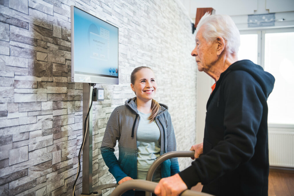 A physiotherapist guiding an elderly man on the HUR SmartBalance machine.